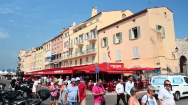 SAINT-TROPEZ, FRANCE - Eylül, 2021: Geleneksel binalar, baraj sokağında birden fazla insan ve kafe var.