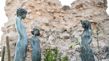 Fransa, Menton 'da tropikal bitkilerle dolu bir parkta heykeller. Arkaplanda duvar
