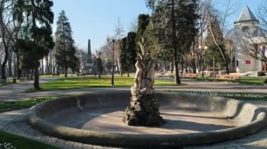 Romanya 'nın Iasi kentindeki Copou Park manzarası. Çeşmeler, sokaklar, çıplak ağaçlar, yeşil çimenler ve çiçek yatakları, insanlar.