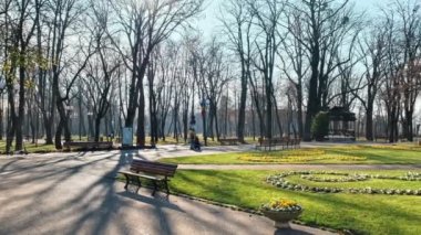 Romanya 'nın Iasi kentindeki Copou Park manzarası. Aslanlar Obelisk, sokaklar, çıplak ağaçlar, yeşil çimenler ve çiçek yatakları, insanlar