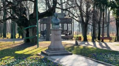 IASI, ROMANIA - 2021 ARALIK: Copou Park manzarası. Mihai Eminescu anıtı, sokak, çıplak ağaçlar, yeşil çimenler, insanlar