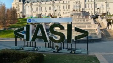 IASI, ROMANIA - 2021 ARALIK: Arka planda Kültür Sarayı ile Iasi imzası. Yürüyen insanlar