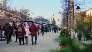 IASI, ROMANIA - 2021 ARALIK: Birden fazla yürüyen insan, Noel Fuarı olan bir cadde, feribot tekerlekleri uzakta.