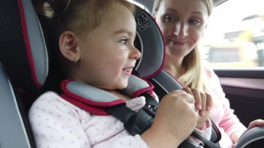 BOSTON, ABD - Eylül 2019: küçük kızı çocuk sandalyeli genç sarışın kadın hareket halindeki bir arabanın arkasında. Yavaş çekim