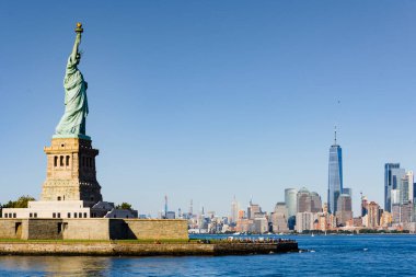 New York, ABD 'deki Özgürlük Anıtı manzarası. Adada çok sayıda turist, arka planda gökdelenler.