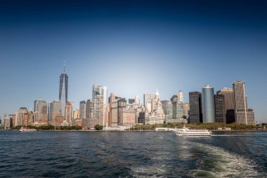 Liberty Island, ABD 'den New York şehri manzarası. Manhattan, birden fazla gökdelen, yüzen feribot.