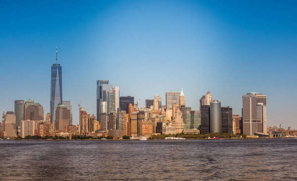 Cityscape of Manhattan and Governors Island from a ferry boat in New York, USA. Multiple skyscrapers in city downtown, water