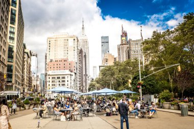 New York, ABD - Eylül 2019: Şehir merkezindeki cadde manzarası. Birden fazla bina, yürüyen ve dinlenen insanlar, gökdelenler, yeşillikler