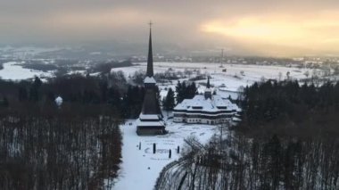 Romanya 'daki Peri-Sapanta Manastırı' nın kışın insansız hava aracı görüntüsü. Ana kilise ve bir bina, etrafında çıplak orman ve kar var.