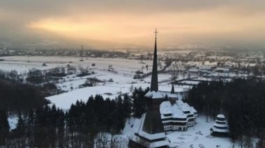 Romanya 'daki Peri-Sapanta Manastırı' nın kışın insansız hava aracı görüntüsü. Ana kilise ve bir bina, etrafında çıplak orman ve kar var.