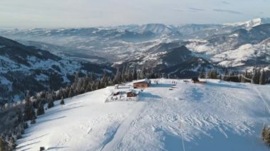 Romanya 'nın kışın Karpatlar' daki bir kayak pistinin insansız hava aracı görüntüsü. Etrafta çıplak orman, kar, teleferik...