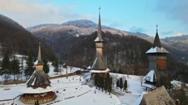Romanya 'daki Barsana Manastırı' nın hava aracı görüntüsü. Ana kilise ve diğer binalar, ziyaretçiler, çıplak orman ve karla kaplı tepeler, kış