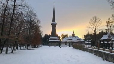 Romanya 'daki Peri-Sapanta Manastırı' nın kışın insansız hava aracı görüntüsü. Ana kilise ve bir bina, ziyaretçiler, çıplak orman ve kar.