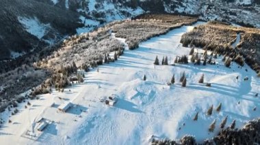 Romanya 'nın kışın Karpatlar' daki bir kayak pistinin insansız hava aracı görüntüsü. Etrafta çıplak orman, kar, teleferik...