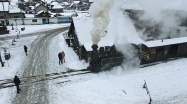VISEU DE SUS, ROMANIA - HAZİRAN 2022: Mocanita buharlı treninin kışın bir tren istasyonundaki görüntüsü, kar, yolcular