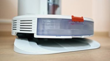 Bir adam rıhtımdaki robot elektrik süpürgesinde filtre değiştiriyor.
