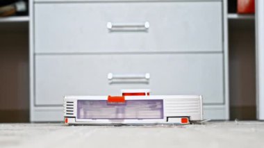Evde robot süpürgeyle çalışıyor, halıda hareket ediyor.