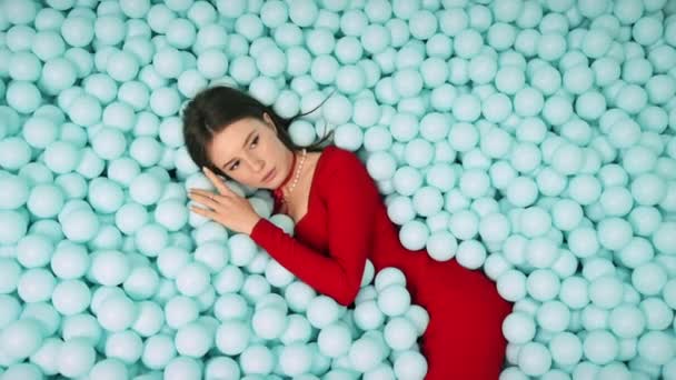 Mujer Joven Vestido Rojo Acostada Posando Montón Bolas Azules Plástico — Vídeo de stock