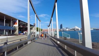 BARCELONA, İSPAN-HAZİRAN 2021: Yürüyen insanlar, köprü, binalar