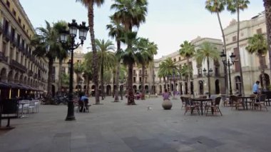 BARCELONA, İSPAN - Haziran 2021: kare. Yürüyen insanlar, yeşillikler, kafeler, antik binalar
