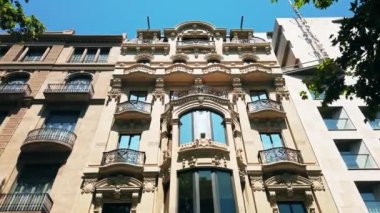BARCELONA, İspanya - Haziran 2021 Barcelona, İspanya Sokakları. Güneşli bir günde klasik tarzda yapılmış eski bir bina, yeşillik.