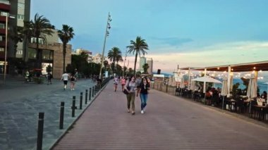 BARCELONA, İspanya - 10 Haziran 2021: Akdeniz kıyısındaki Embankment Caddesi, gün batımında. Birçok insan, otel ve avuç içi.