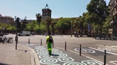 BARCELONA, İSPAN-HAZİRAN 2021: Yürüyen insanlarla dolu bir meydan, güneşli bir günde klasik tarz ve yeşillikte yapılmış eski binalar