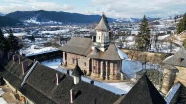 Romanya 'nın Vatra Moldovitei kentindeki Moldovita Manastırı' nın hava aracı görüntüsü. Kar, turistlerle dolu avlu, çevrede evler