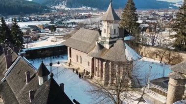 Romanya 'nın Vatra Moldovitei kentindeki Moldovita Manastırı' nın hava aracı görüntüsü. Kar, turistlerle dolu avlu, çevrede evler