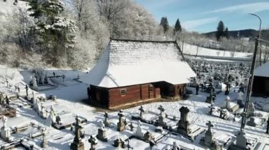 Romanya 'nın Putna kentindeki Ahşap Kilisenin insansız hava aracı görüntüsü. Mezar taşlı, karlı.