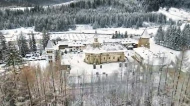 Romanya 'daki Putna Manastırı' nın kışın insansız hava aracı görüntüsü. İç avlu, çıplak ağaçlar, kar, tepeler, vadi