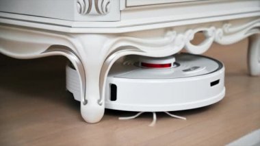 CHISINAU, MOLDOVA - Şubat 2022: Evde çalışan Roborock robotik elektrik süpürgesi. Mobilyaların altında yerde hareket ediyor. Yavaş çekim