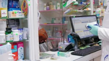 CHISINAU, MOLDOVA - FEBRUARY, 2022: Eczanedeki müşteriler için ilaçları kontrol eden eczacı