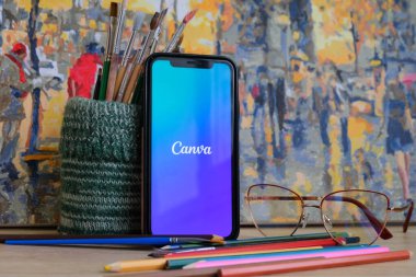 CHISINAU, MOLDOVA - FEBRUARY, 2022: Artistik arka planda fırçalar ve renkli pastel boyalarla çevrili bir telefon ekranındaki devasa tasarım uygulama kanvasının logosu