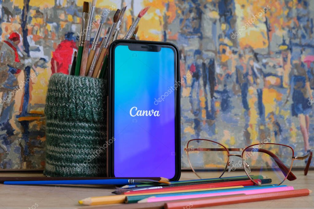 CHISINAU, MOLDOVA - FEBRUARY, 2022 : The logo of the garphic-design app Canva on a phone screen surrounded by brushes and colorful crayons on an artistic background