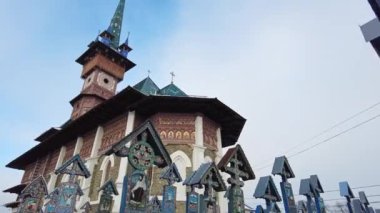 SAPANTA, ROMANIA - HAZİRAN, 2022 Kışın Merry Mezarlığı 'ndaki çoklu mezar taşı ve kilise manzarası