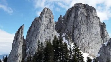 Romanya 'daki Karpatlar' ın insansız hava aracı görüntüsü. Rocky tepeleri ve vadileri kısmen kar ormanlarıyla kaplı.