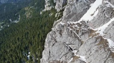 Romanya 'daki Karpatlar' ın insansız hava aracı görüntüsü. Rocky tepeleri ve vadileri kısmen kar ormanlarıyla kaplı.