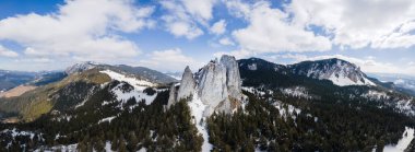 Romanya 'nın Bahar Karpatları' nın hava aracı panoramik görüntüsü. Rocky tepeleri, tepeler ve vadiler kısmen kar ormanlarıyla kaplı.