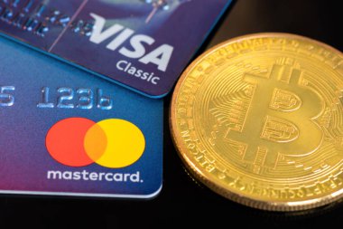 CHISINAU, MOLDOVA - Mart 2022: Fiziksel Bitcoin altın madeni para, Mastercard ve yakınlardaki Visa kartı