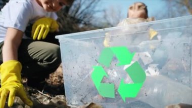 Erkek ve kız, kirlenmiş bir temizleme kabında plastik çöp topluyor tişörtlerdeki geri dönüşüm tabelalarını topluyor. Yavaş çekim
