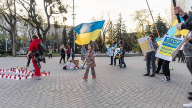 CHISINAU, MOLDOVA - Nisan 2022: Rusya 'nın Ukrayna' nın merkezdeki işgaline karşı protestolar. Ukrayna bayrakları ve posterleri olan bir sürü insan ve çocuk. Yere yazıt.