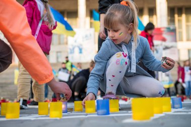 CHISINAU, MOLDOVA - Nisan 2022: Rusya 'nın Ukrayna' nın merkezdeki işgaline karşı protestolar. Ukrayna bayrağı taşıyan çocuk sığınak lambaları yakıyor. Yere yazıt.