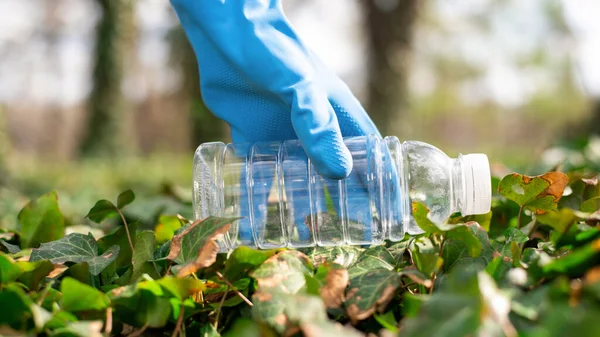 Man at plastic garbage collecting in a polluted park. Rubber gloves, taking a plastic bottle