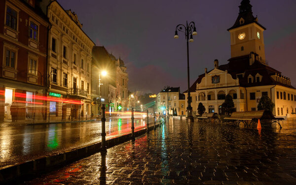 Streetscape of the central place in the south-eastern of Transylvania full of people and local food places, The Black Church in the background at night