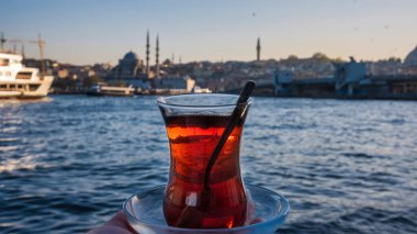 İstanbul 'daki deniz limanının deniz manzarasının ön planında bir fincan Türk meyveli çayı