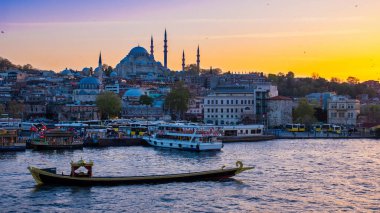 İstanbul limanının ve kentsel manzaranın önünden geçen Türk teknesinin akşam altın saati manzarası