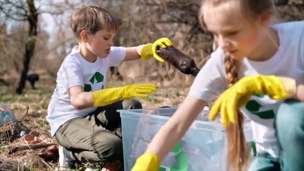 Chlapec Dívka Sbírají Plastové Odpadky Kontejneru Znečištěné Mýtině Recyklační Značky — Stock video