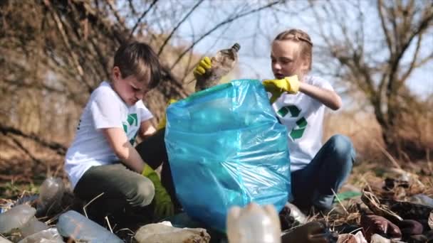 Jungen Und Mädchen Sammeln Plastikmüll Einer Tüte Auf Einer Verschmutzten — Stockvideo