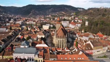 Romanya 'nın eski Brasov merkezindeki Kara Kilise' nin insansız hava aracı görüntüsü. Çevresindeki eski binalar, yeşillikli tepeler.